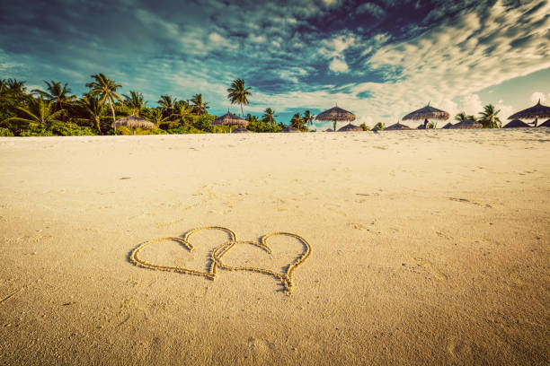 istock Two hearts drawn on sand of a tropical beach. Vintage 916582456