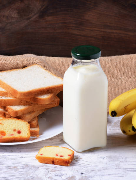 primo tempo di latte, pane, torta e banana a tavola - milk bread foto e immagini stock