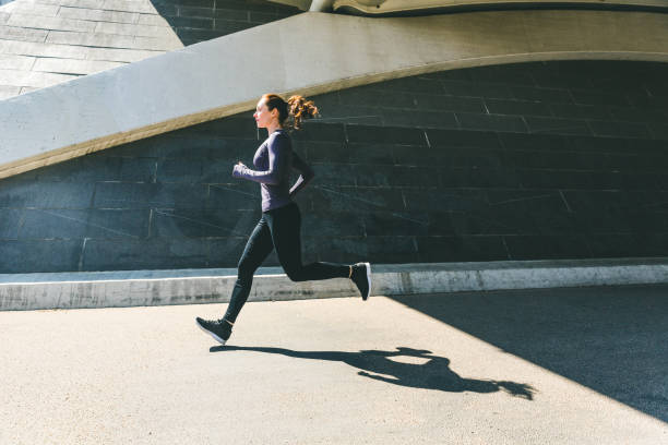 woman jogging or running, side view with shadow - running jogging urban scene city life imagens e fotografias de stock