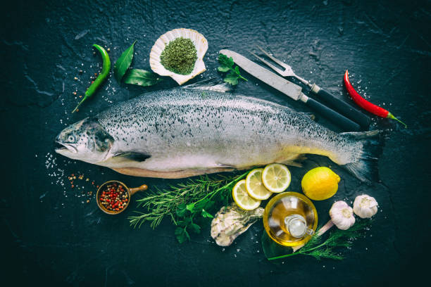 Fresh salmon fish with seasoning on black stone Fresh salmon fish with seasoning on black stone background sockeye salmon filet stock pictures, royalty-free photos & images