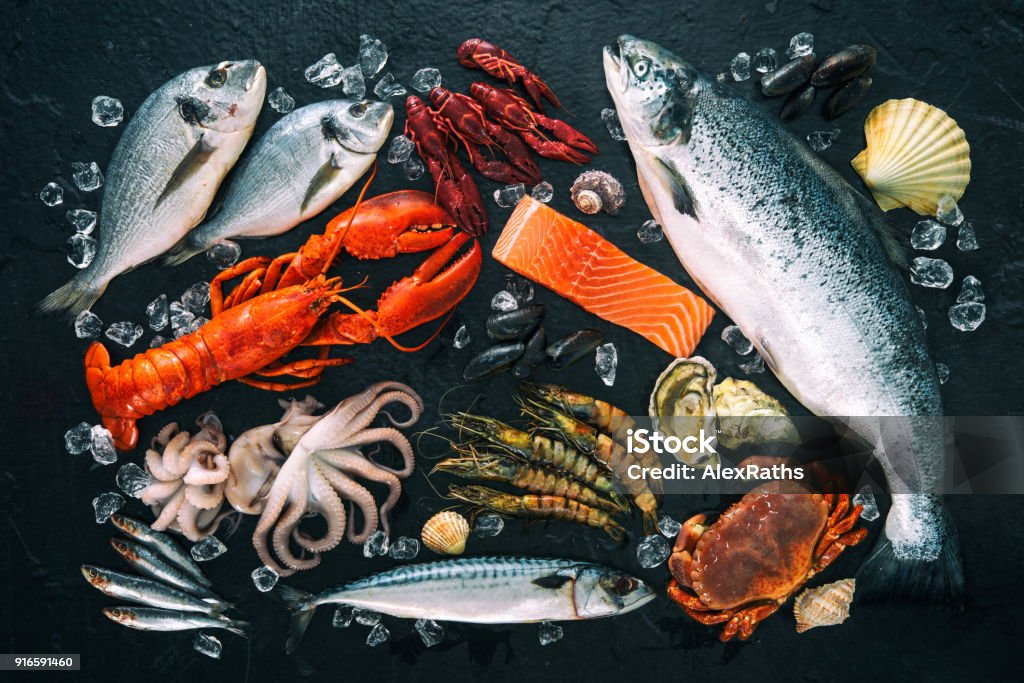 Fresh fish and seafood arrangement on black stone Fresh fish and seafood arrangement on black stone background Seafood Stock Photo