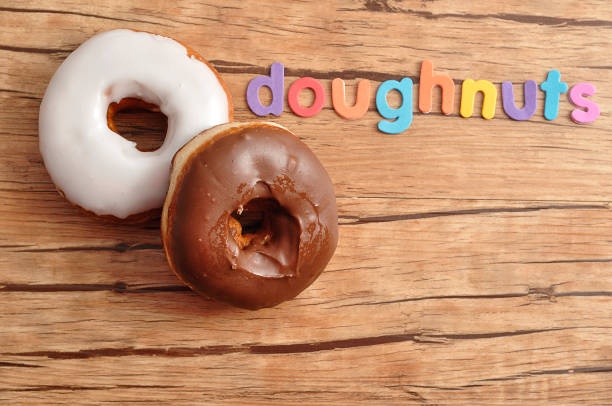 istock Two doughnuts with the word doughnuts on a wooden background 916591548