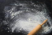 Baking background with the rolling pin and flour. On the dark table