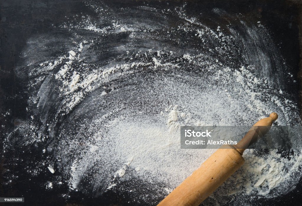 Baking background with the rolling pin and flour. On the dark table Baking background with the rolling pin and flour. On the dark table. Copy space for text. Top view Flour Stock Photo