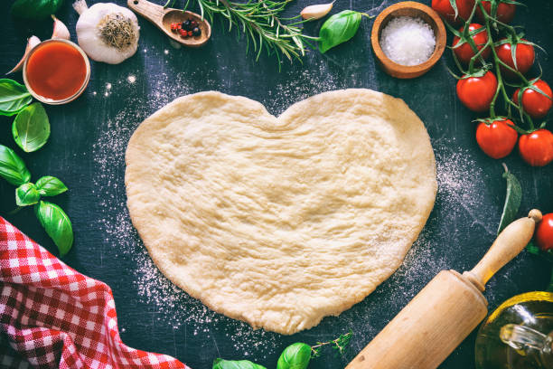 ingredienti per cucinare pizza o pasta con pasta a forma di cuore - garlic cooking oil cutting board horizontal foto e immagini stock