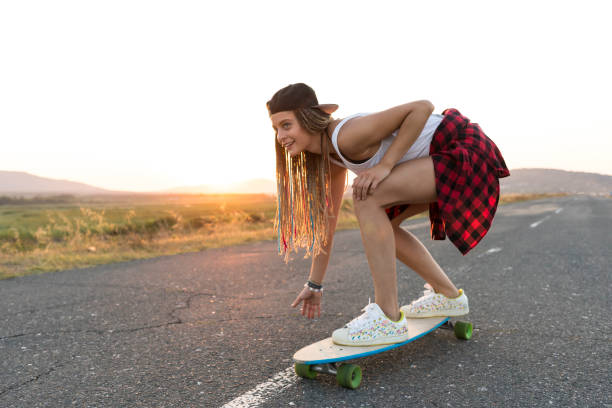 istock Beautiful girl with longboard skating on road 916599198