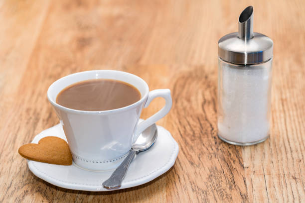 white cup filled with delicious cappuccino next to sugar bowl full of cane sugar