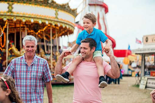 Multi-generation family of men visit the fairground to enjoy the rides together