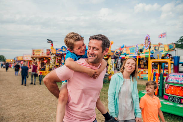 Family at the Fairground Family enjoying time at the fairground. Dad is carrying his son on his back carnival children stock pictures, royalty-free photos & images