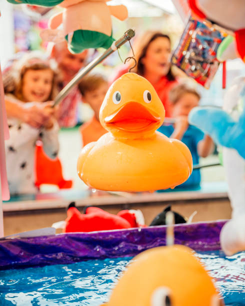 Hook a Duck at the Fairground Grandparents helping their grandchildren hook a duck on a side show at a fairground. Focus on the Duck duck family stock pictures, royalty-free photos & images