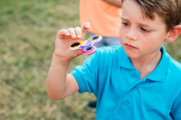 kleine jongen spelen met een fidget spinner - handspinner stockfoto's en -beelden