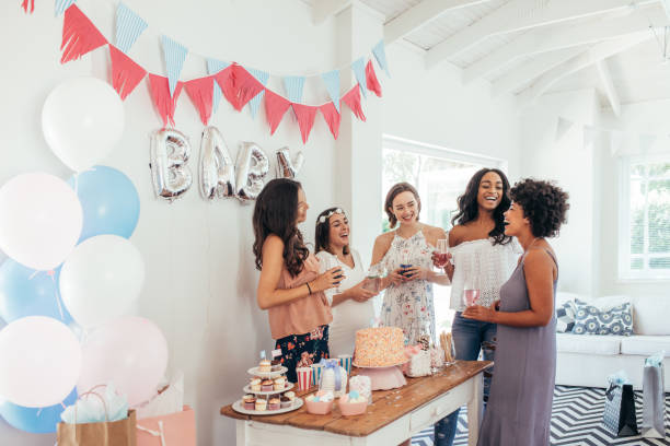 Diverse women together at baby shower Group of diverse women together at baby shower. Smiling young pregnant woman celebrating baby shower with best friends. baby shower stock pictures, royalty-free photos & images