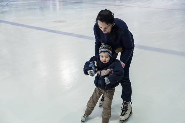 istock happy little boy and his mother learning ice-skating 916612806