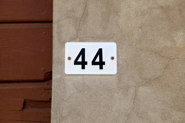 istock Old vintage house number 44 on stone wall. 916622154