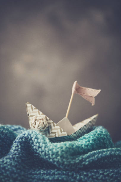 istock Handmade origami boat on handmade waves with stormy sky 916628150