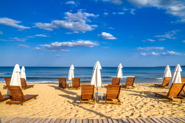 Coastal landscape - Beach umbrellas and loungers on the sandy seashore Coastal landscape - Beach umbrellas and loungers on the sandy seashore, the Kavatsi bay near city of Sozopol in Bulgaria bulgaria stock pictures, royalty-free photos & images