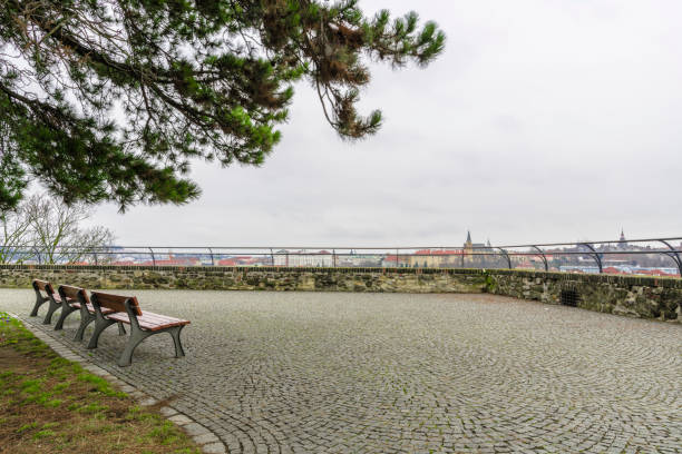 Three benches at the turn of a stone-paved pedestrian walkway passing through the wall of the old fortress.
