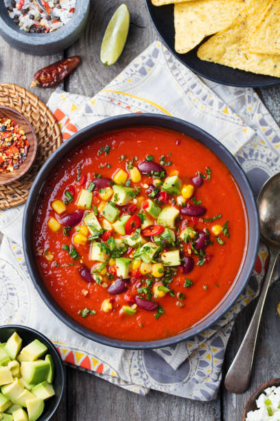 istock Mexican tomato, bean, bell pepper soup in black bowl. Top view 916644066