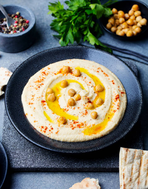 istock Hummus, chickpea dip, with spices in a black plate on grey stone background. 916644202