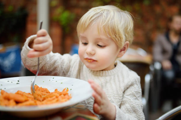 Cute toddler boy eating pasta in Italian indoors restaurant Cute toddler boy eating pasta in Italian indoors restaurant. Healthy/unhealthy food for little kids kids eating noodles stock pictures, royalty-free photos & images