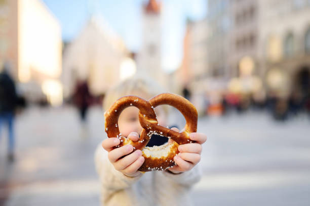 pouco turista segurando tradicional pretzel da baviera, em munique - 5937 - fotografias e filmes do acervo