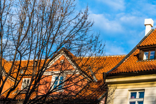 Transparent blue morning sky over the red tiled roofs of Prague's houses.