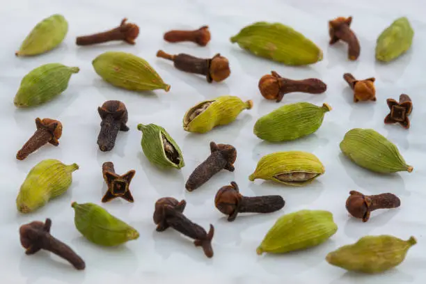 beautiful cardamom pods and cloves on top of carrara marble coutertop