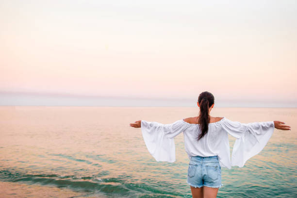istock Young woman on the beach at sunset 916664320