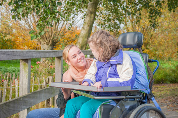 Working together with disability A disabled child in a wheelchair being cared for by a voluntary care worker personal care aid stock pictures, royalty-free photos & images