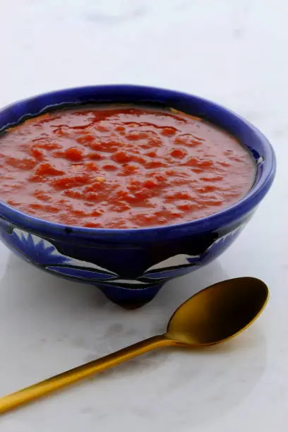 Artisan mexican hot salsa in vintage talavera bowl, with a delicious fresh hot flavor,  on vintage carrara marble table.