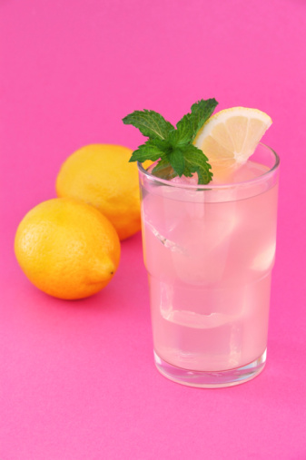 A refreshing glass of pink lemonade, garnished with a sprig of mint.