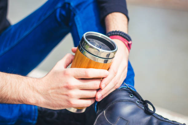 istock man holding coffee to go in thermos. 916680142