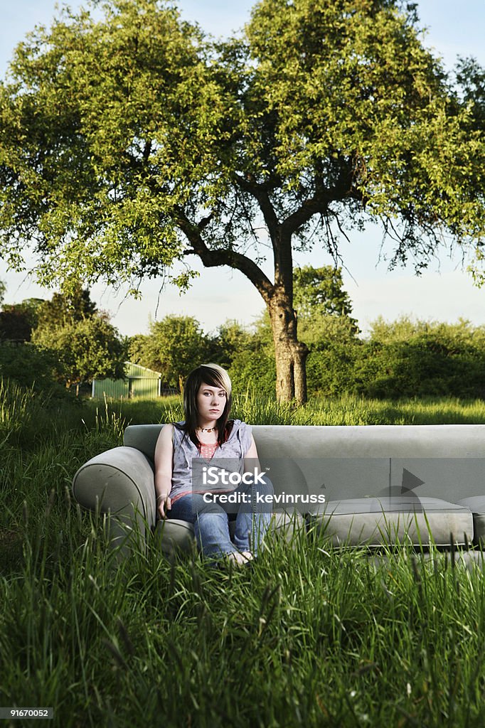 Chica joven sentado en un sofá en la sala de estar al aire libre - Foto de stock de Campo - Tierra cultivada libre de derechos