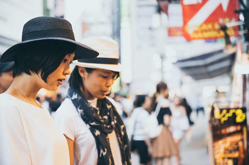 Beautiful east Asian women exploring famous tourist destination of Shibuya crossing's nearby shopping district.