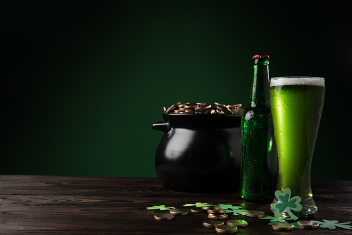 pot with golden coins and green beer on table, st patricks day concept