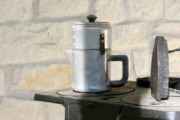 istock Old aluminum coffee pot  and iron atop mini stove. 91670941
