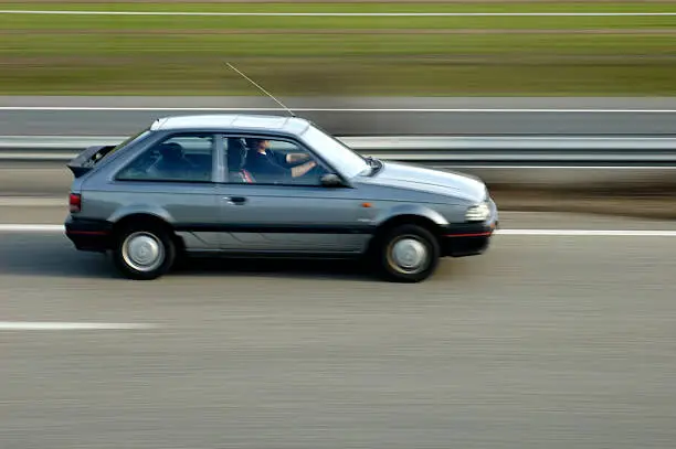 A motorist drives down the highway. Motion blur on the car and the background. Space for text on the road or on the blurred background.