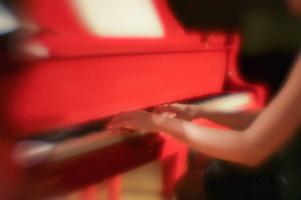 Gentle hands and red grand piano. Creative lens, soft focus.