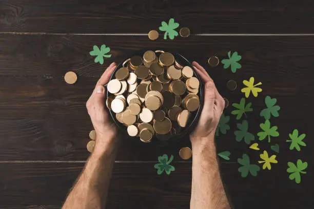 Photo of cropped image of man holding pot with golden coins, st patricks day concept