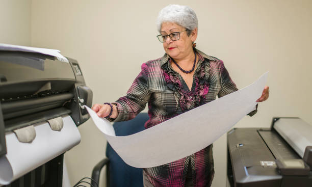 istock Senior silver-haired woman, engeneer, using the commercial wide format printer 916738374
