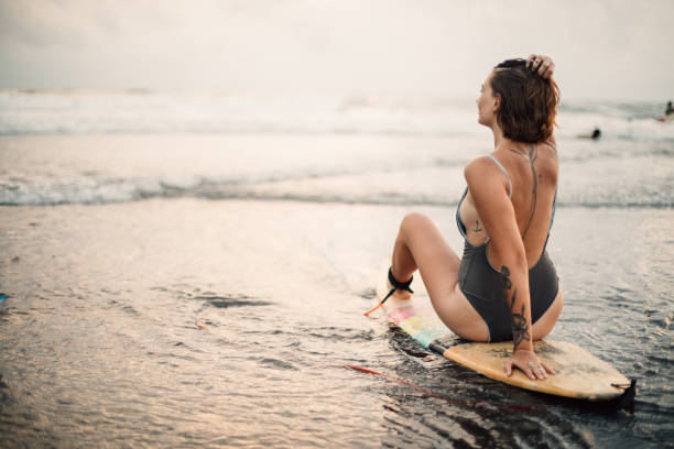 istock Surfer girl at the beach at sunset 916747242