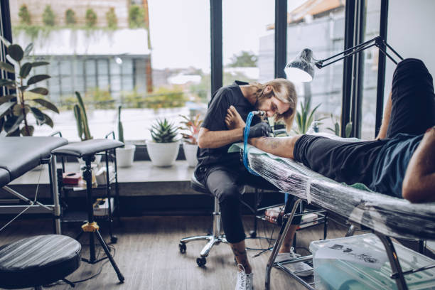istock Young artist making tattoo on man's leg in studio 916749814