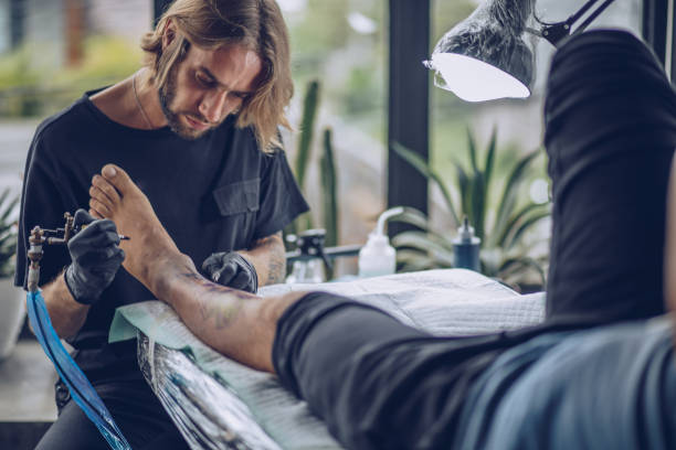 istock Young artist making tattoo on man's leg 916752622