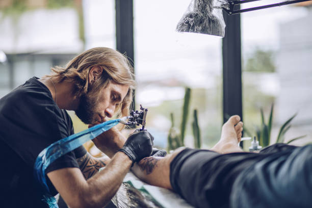 istock Artist making tattoo on man's leg in studio 916752674