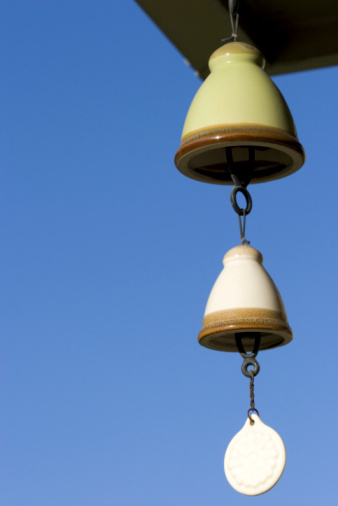 Bell shaped wind chimes with bright clear blue sky behind. Room for text.