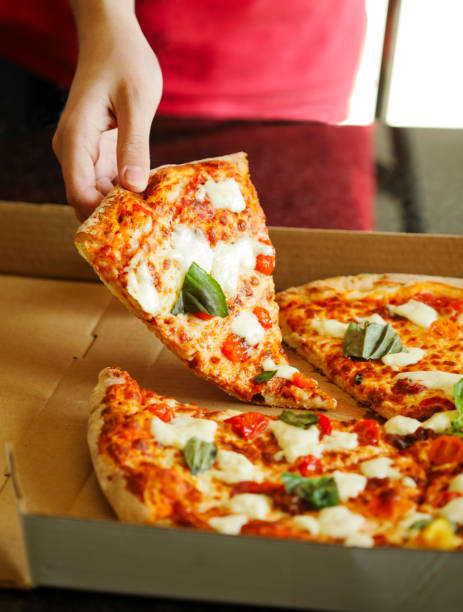 istock Person's hand taking slices of pizza. 916775936