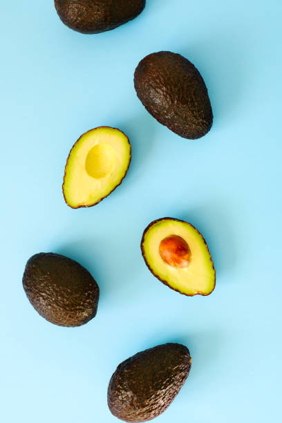 istock Avocado halves and whole on a blue speckle, top viev. 916776146