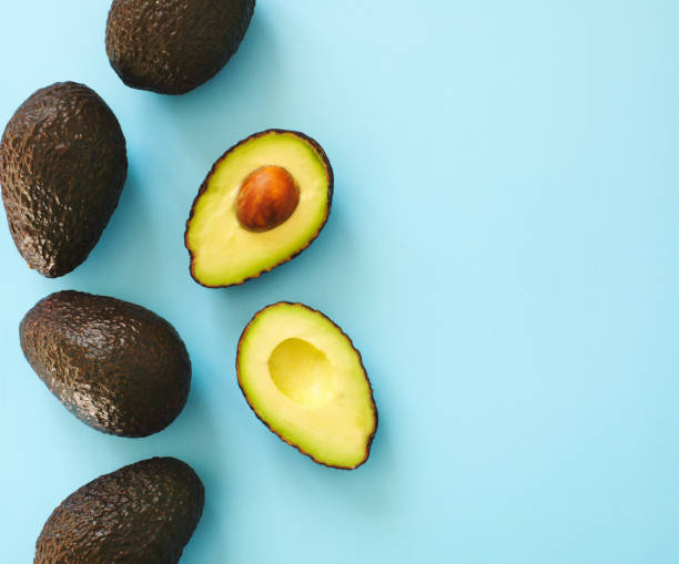 istock Avocado halves and whole on a blue speckle, top viev. 916776354