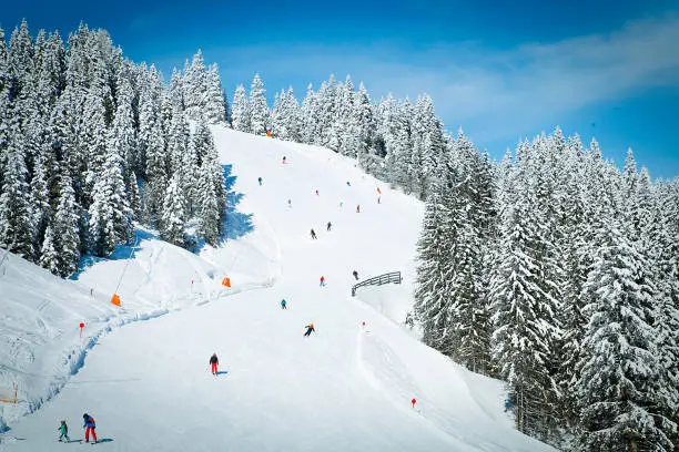 Ski slope with skiers in Austrian Alps mountains