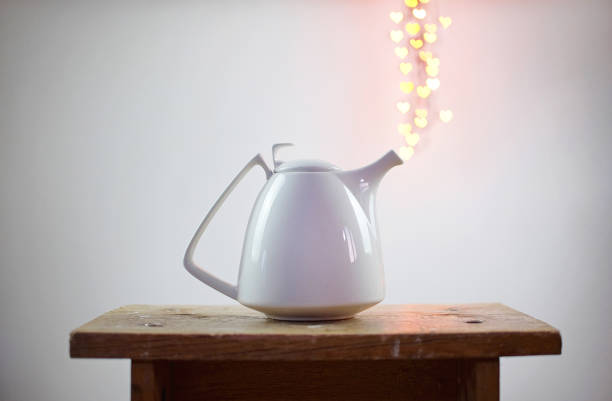 white teapot and heart shaped bokeh over it on white background. Valentine's Day concept